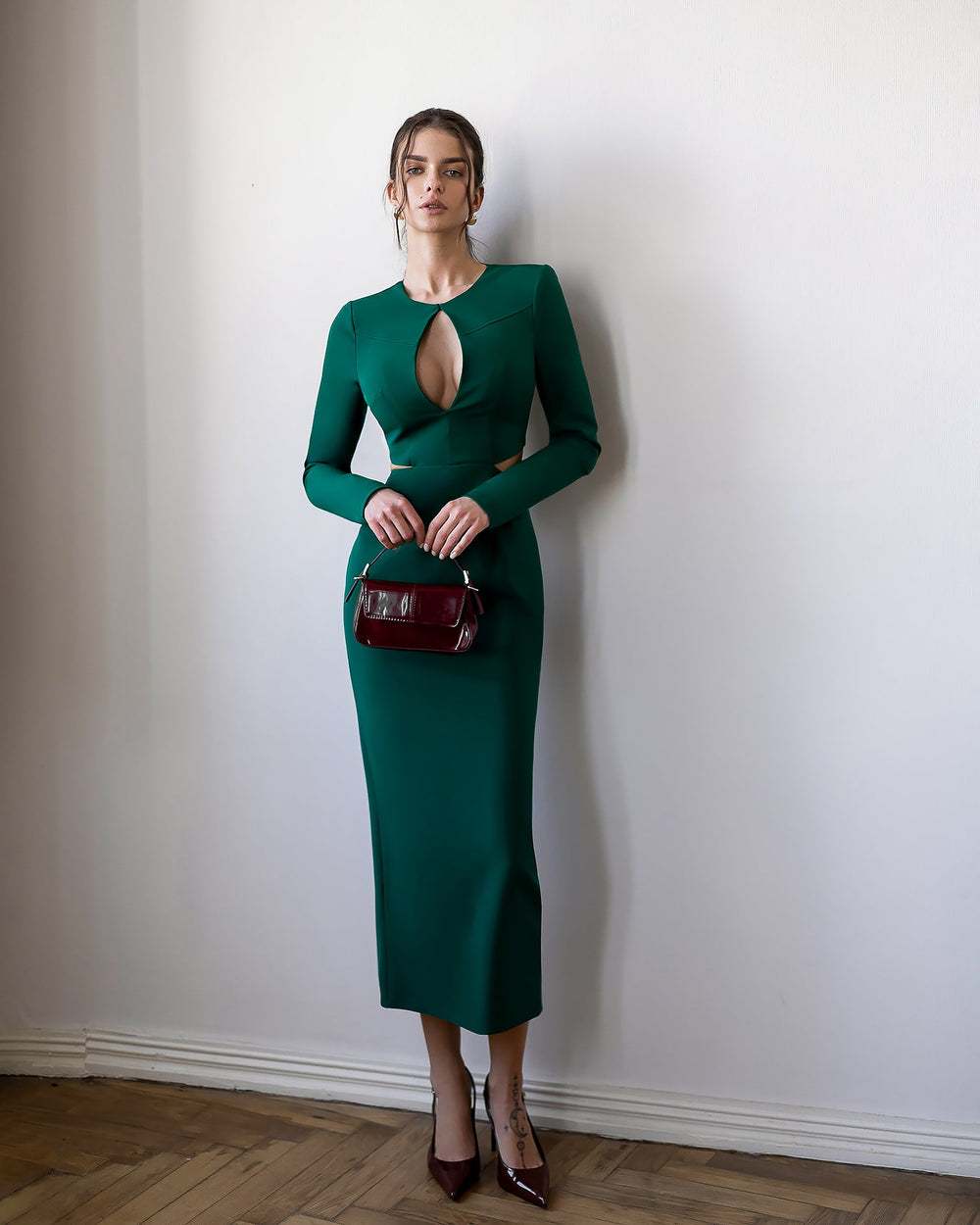 Cavirelle Dress in emerald green, front view of model with side bag accessory