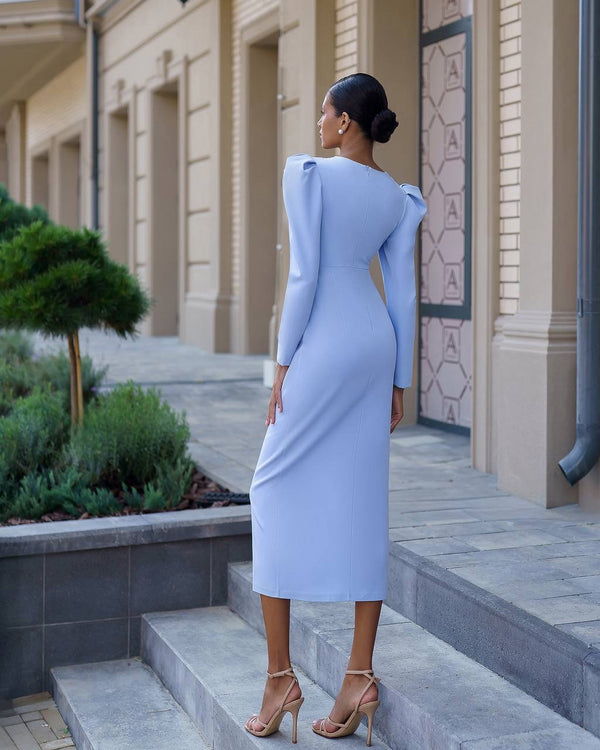 Woman in a light blue dress standing on steps outside a building