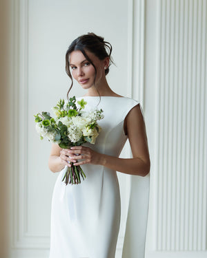 Athena Cape Gown milk white, outdoor setting with bouquet