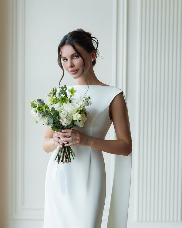 Athena Cape Gown milk white, outdoor setting with bouquet
