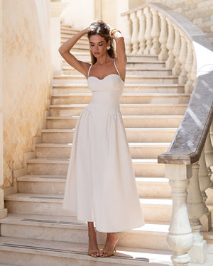 Odette Midi Dress in black, full-length pose in modern setting