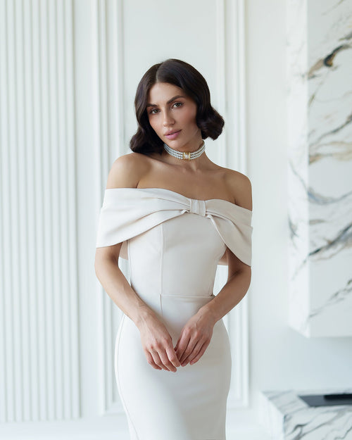 Woman wearing a white off-shoulder dress in a marble interior setting